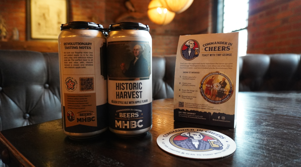 four back of Historic Harvest ale on a table at Mill House Brewing Company in Poughkeepsie with warm lighting and exposed brick walls behind the booth
